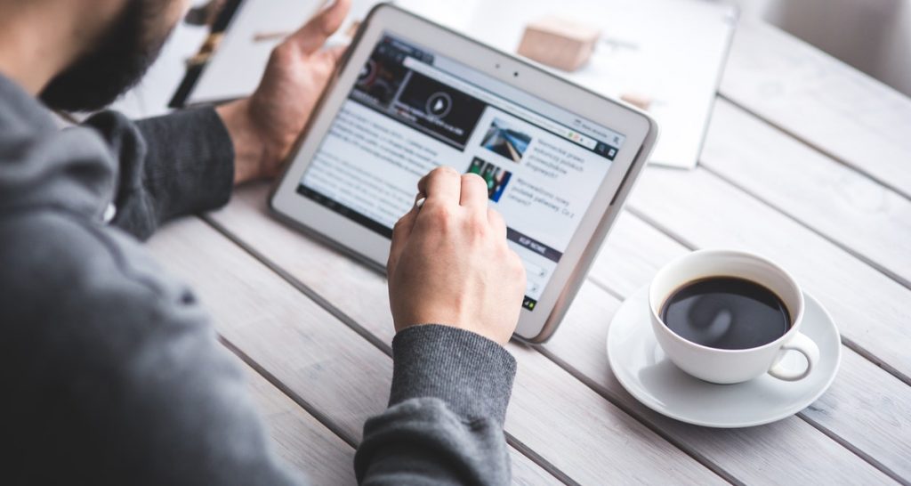 man holding tablet in coffee shop