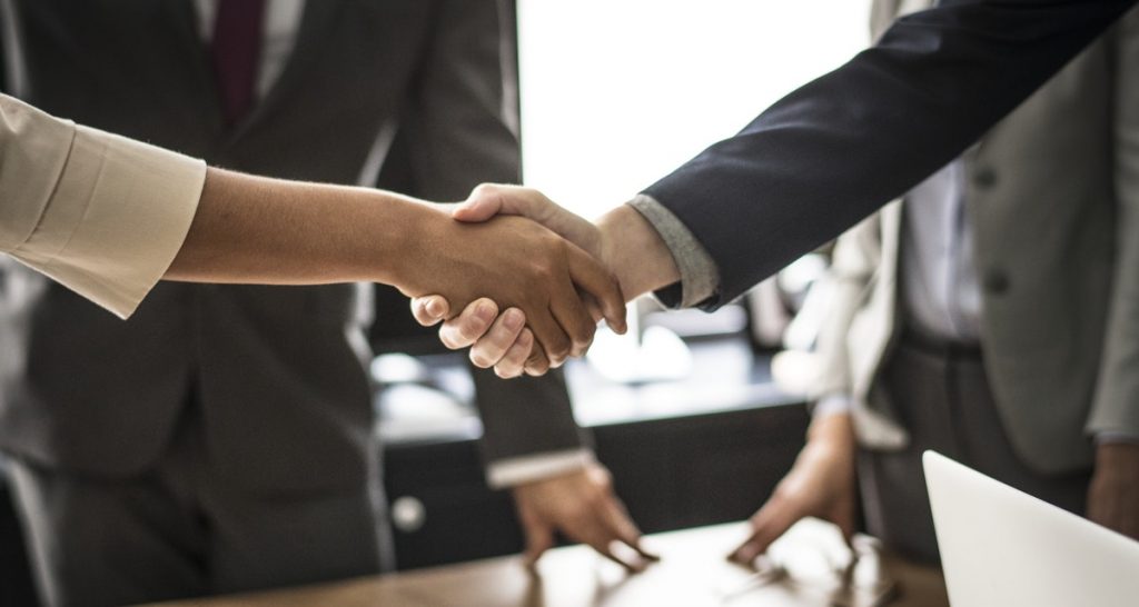 man shaking hands wearing blue coat